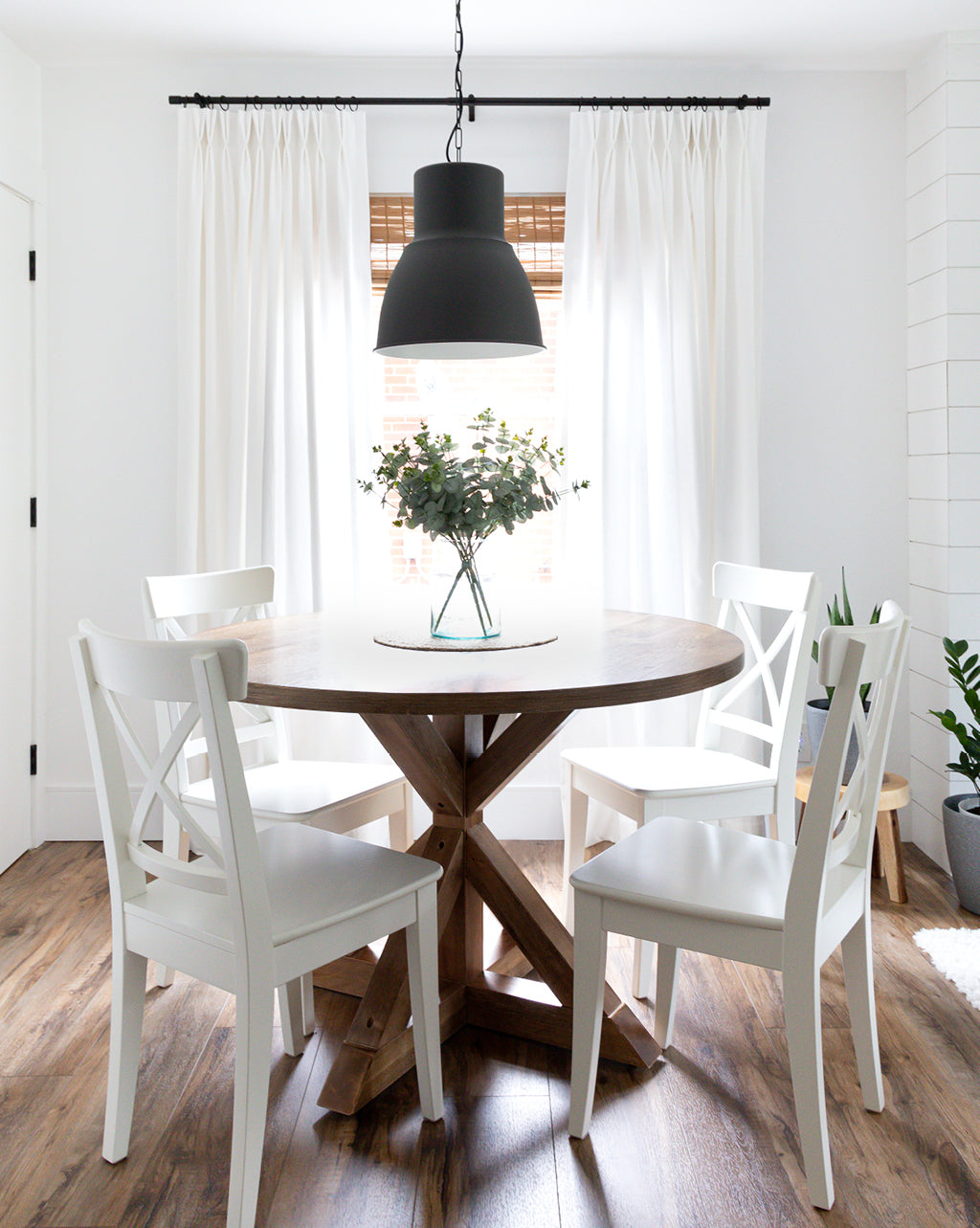 White and beige living room with off-white double pinch drapery panels. White arm chairs in centre and long wooden coffee table