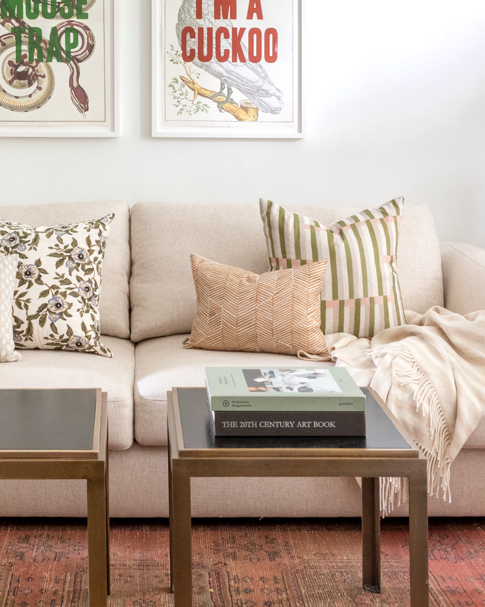 Rectangle rust chevron Imogen Heath patterned pillow sitting on white sofa with geometric square complimentary pillow behind it.