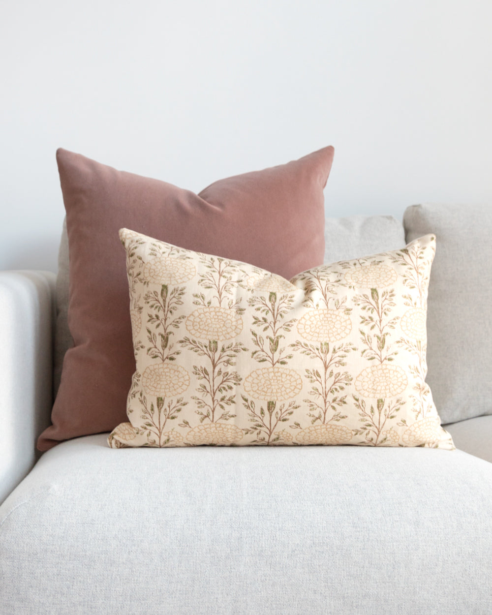 Lisa Fine Textiles muted floral print pillow sitting on white sofa with complimentary pink mohair pillow