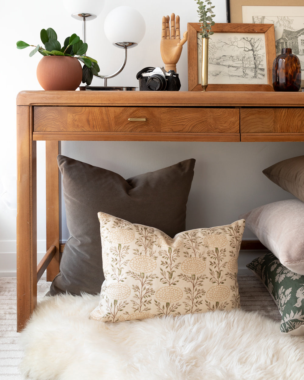 Lisa Fine Textiles muted floral print pillow sitting under console table with complimentary mohair pillow