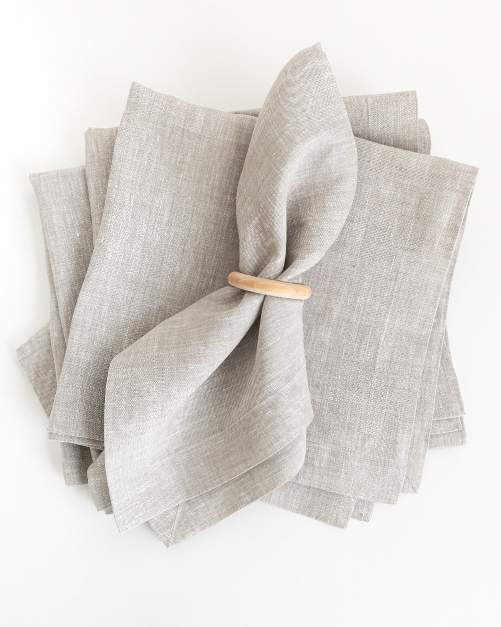 Natural beige linen napkin in wood napkin ring holder on stalk of napkins