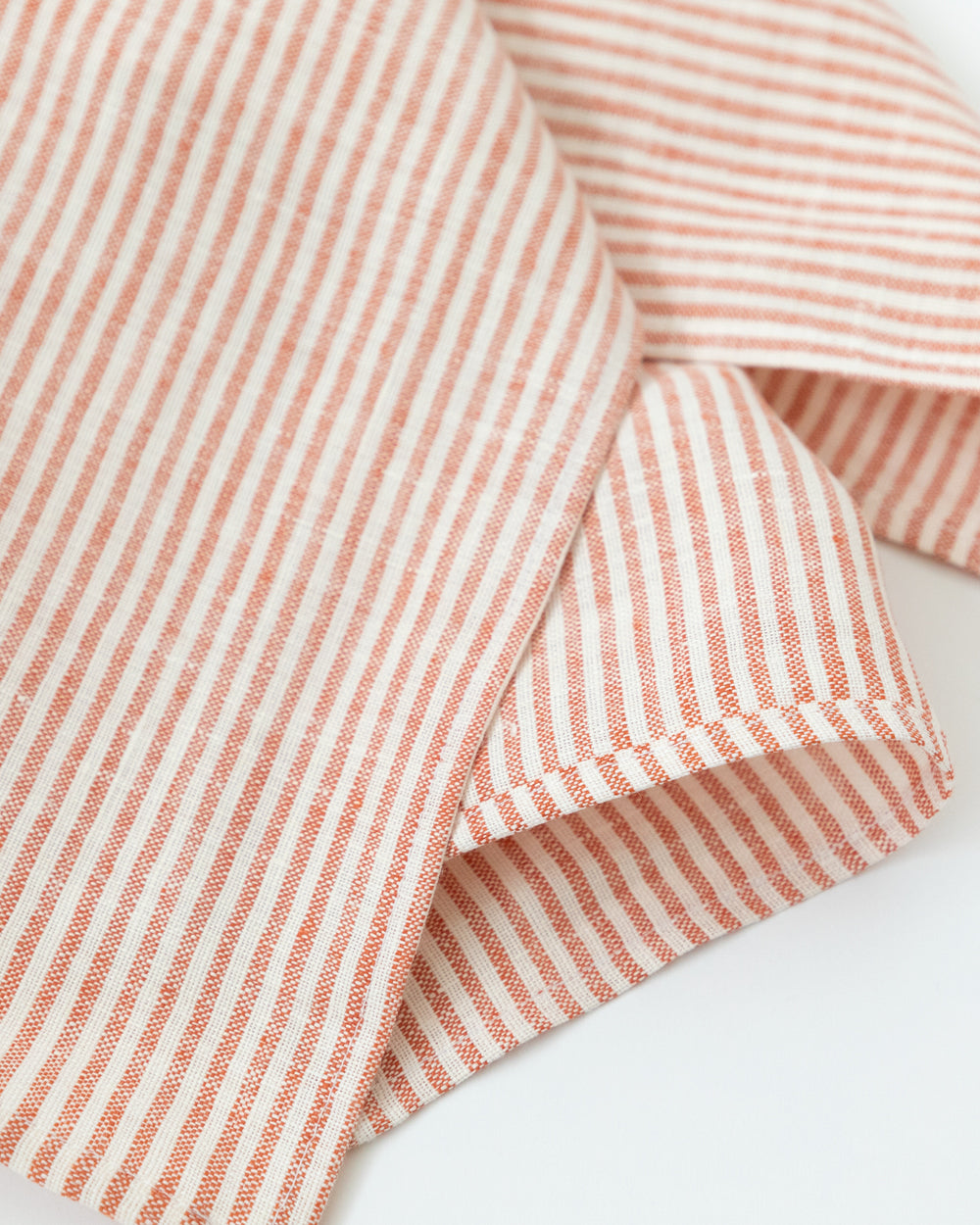 Detailed close up of a striped linen tea towel is a beautiful mix of cream and vermillion red
