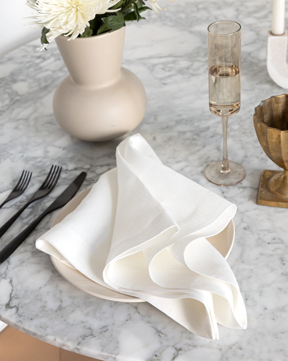 Oversized white linen napkin on marble table with flatware