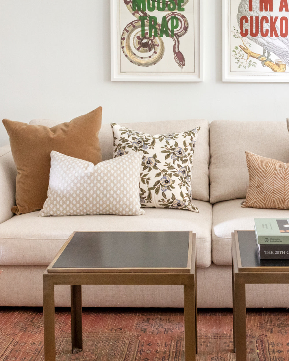 ikat inspired dot pillow in a creamy white on a natural beige background sitting on a white sofa in a living room with complimentary pillows