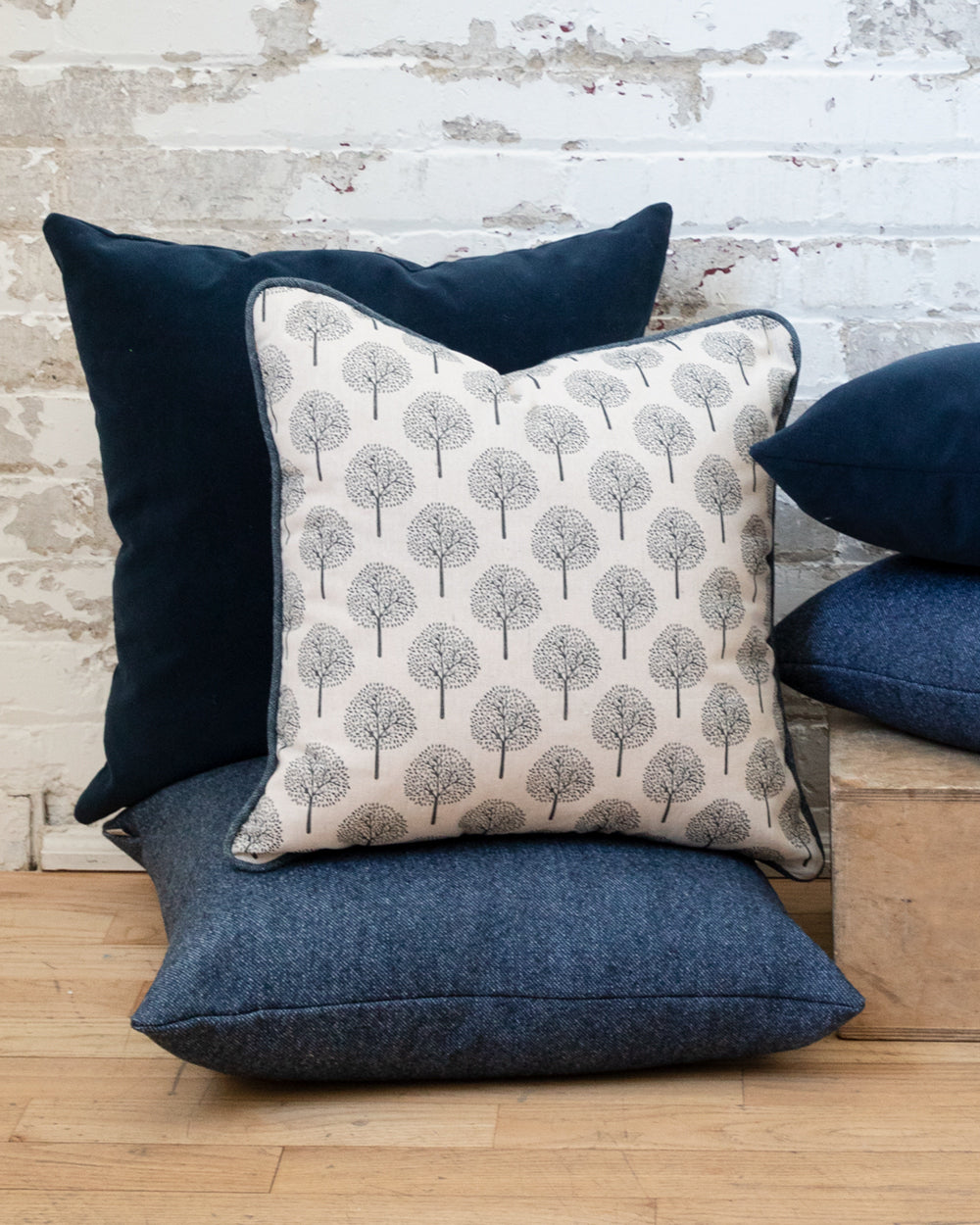Dark blue and white cotton pillow with tree motif, sitting on complimentary dark blue pillows