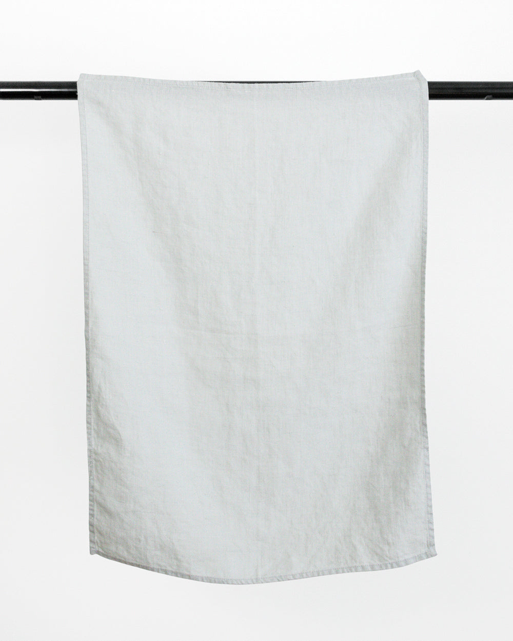 Blue stonewashed linen tea towel hanging on black rod