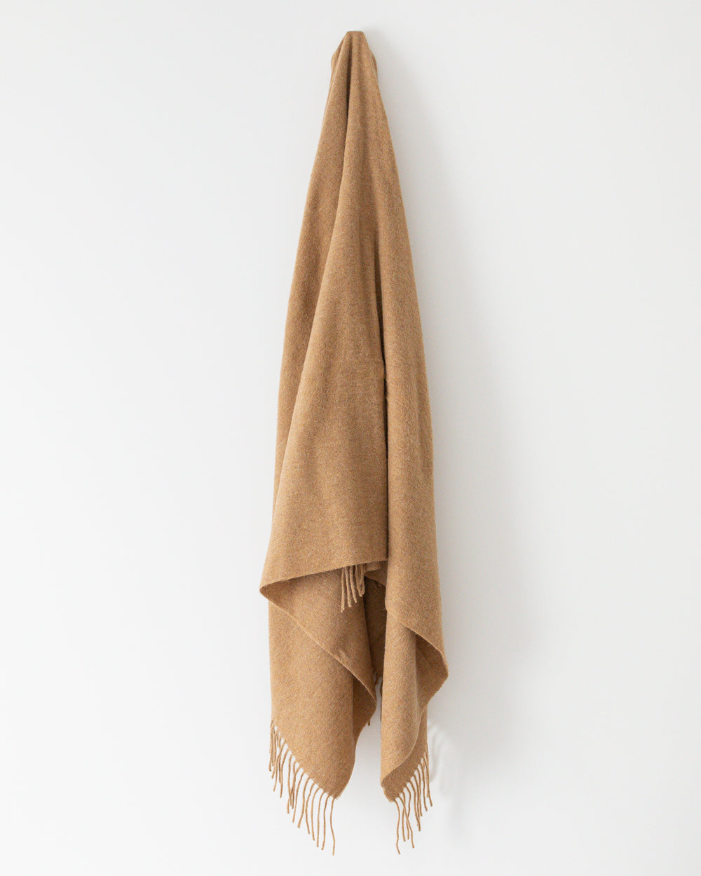 Caramel Alpaca wool throw with tassels hanging on hook
