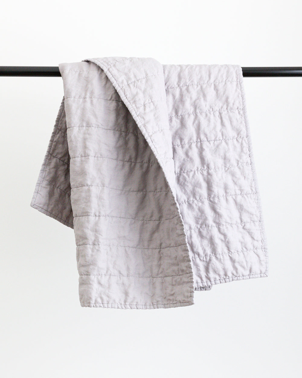 Classic light grey quilt folded over black rod