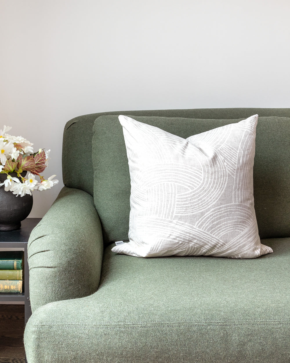 Grey and white organic swirl pattern pillow on green sofa