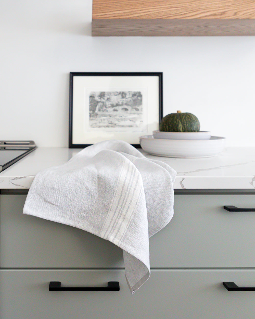 stone-washed linen tea towel is a soft, pale grey with a white stripe on counter