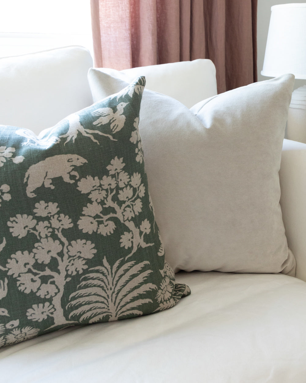 Green and beige woodland print pillow on white sofa