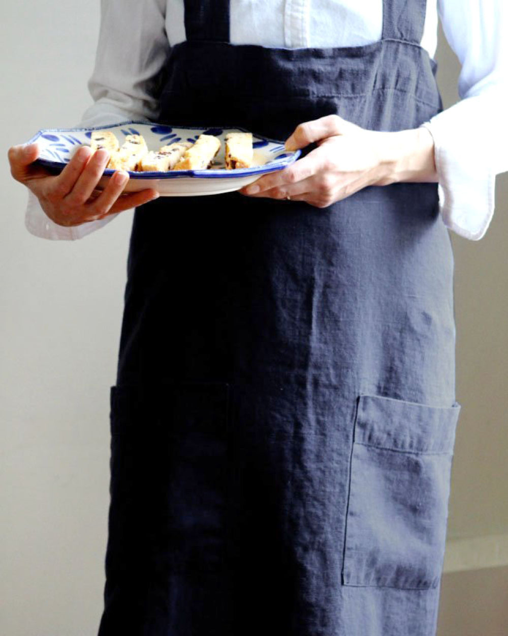 Person holding plate with food and wearing Annie Linen Smock Apron in Ink Blue 
