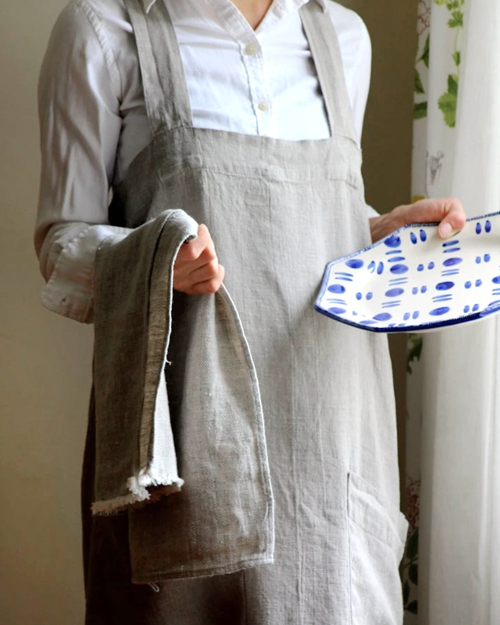 Person holding plate and dish towel wearing natural stone-washed linen apron