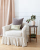 Striped Imogen Heath rectangle pillow and mauve mohair square pillow sitting on white sofa.