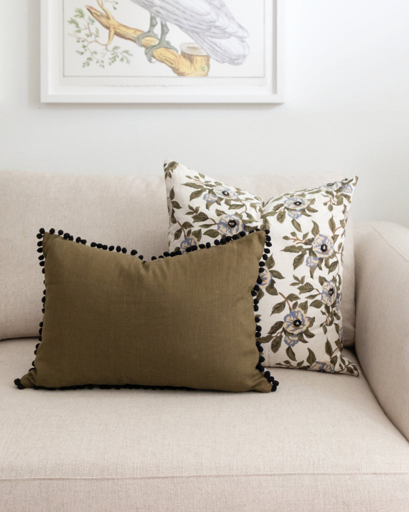 Pom pom olive green linen lumbar pillow with complimentary floral pillow on white sofa