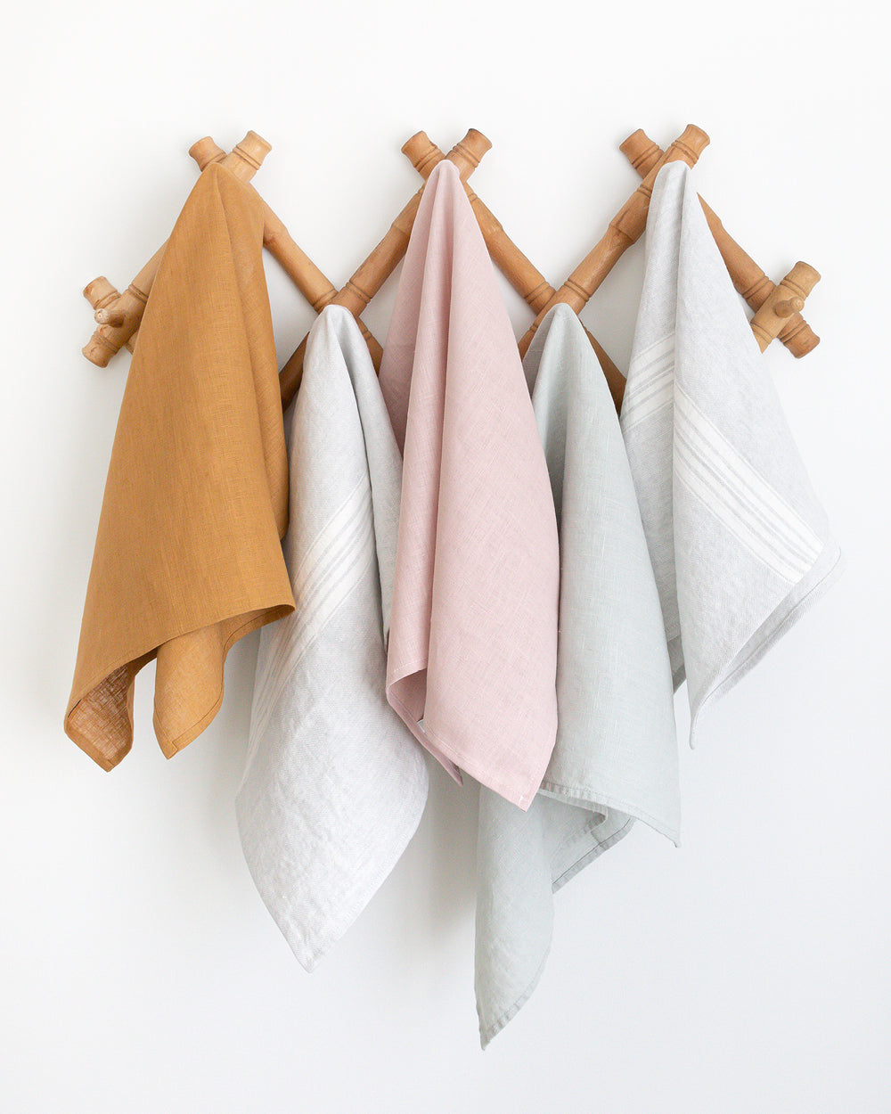 Collection of linen tea towel on wall rack.
