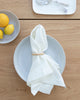 Classic white linen napkin with napkin ring holder sitting on plate and wood table