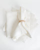 Classic white linen napkin with napkin ring holder sitting on stack of napkins