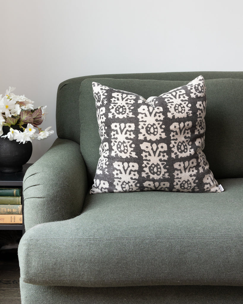 Black and white hand-blocked linen pillow sitting on green sofa
