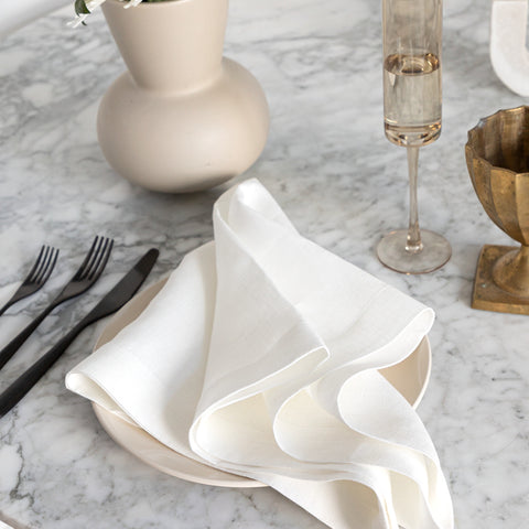 Oversized white linen napkin on marble table with flatware