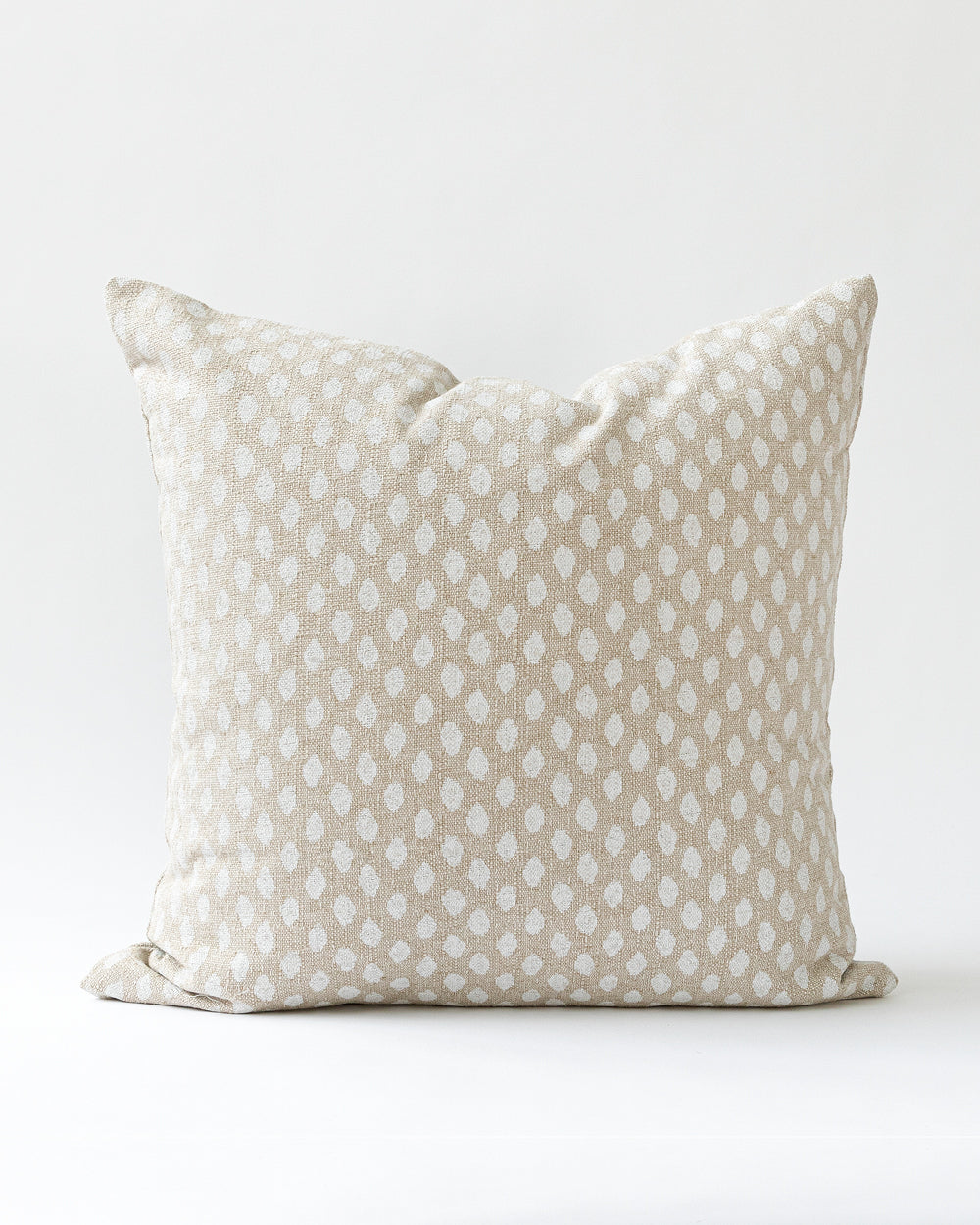 Square ikat inspired dot pillow in a creamy white on a natural beige background