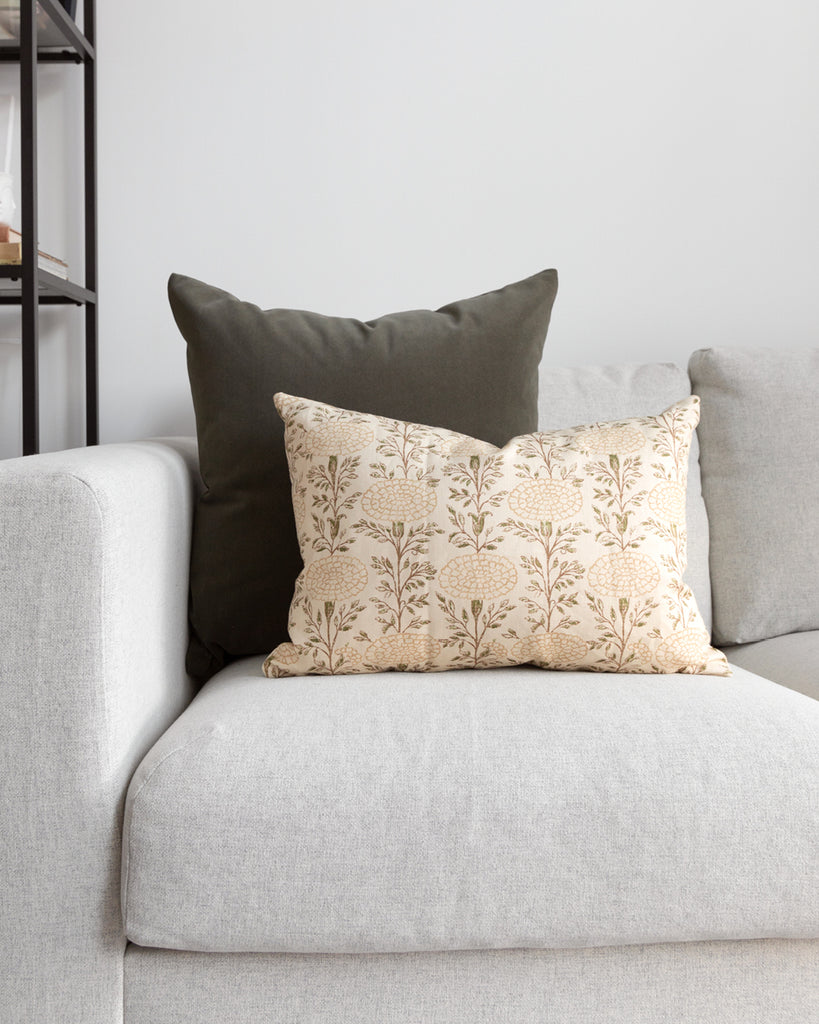 Dark forest green velvet pillow on white sofa with beige floral complimentary pillow