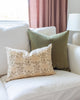 Soft olive green velvet pillow on white sofa with beige floral complimentary pillow