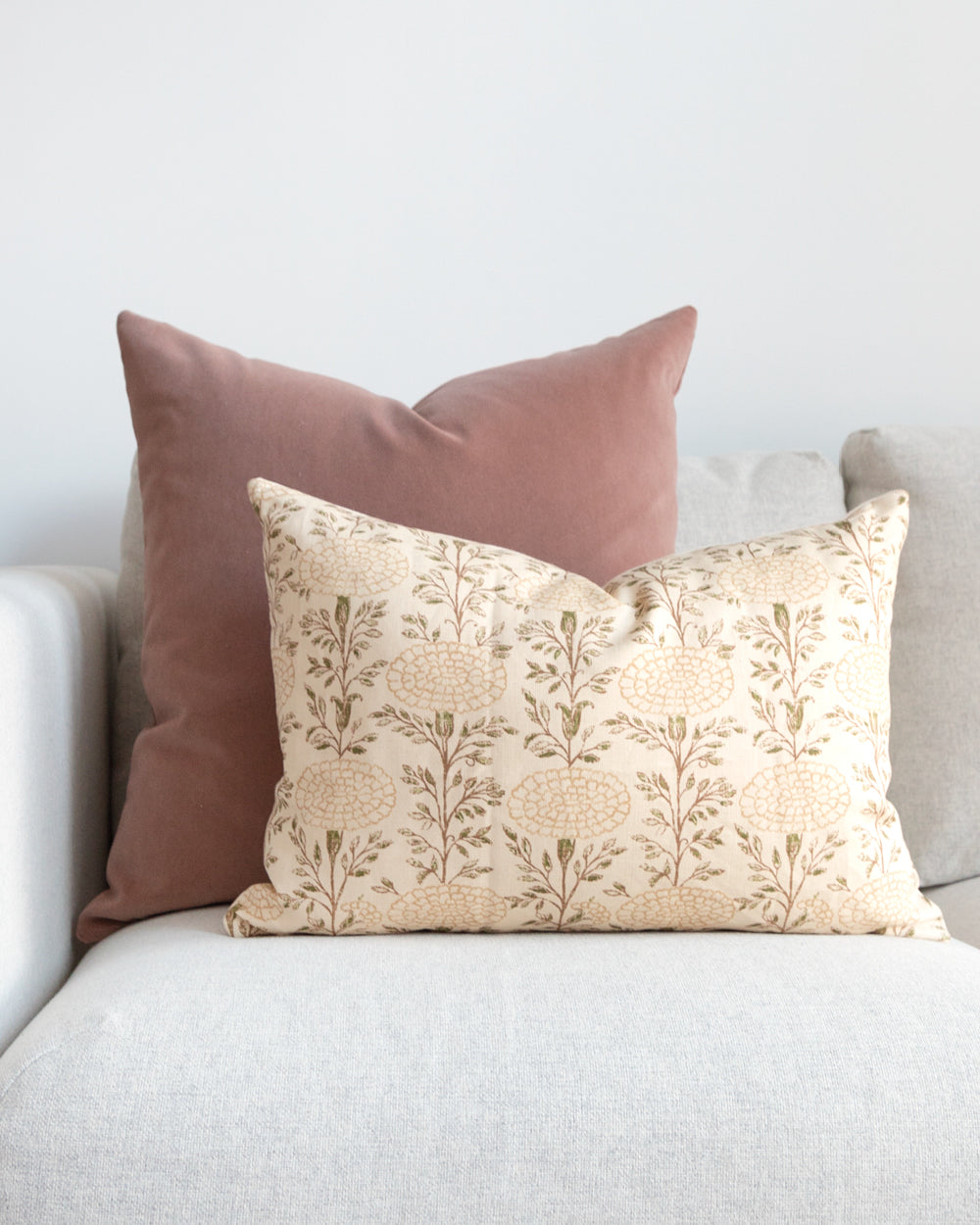 Rose velvet pillow on white sofa with beige floral complimentary pillow.