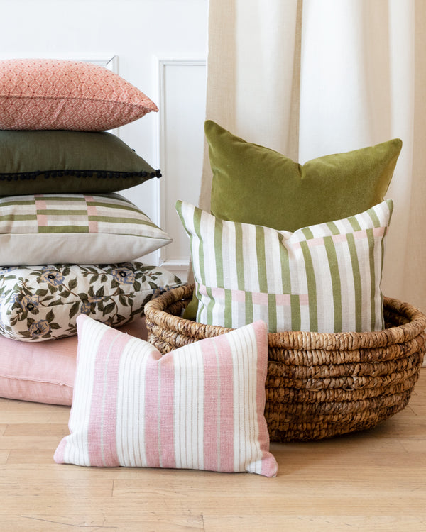 Pink and beige cotton striped pillow with stack of other complimentary Hemme pillows