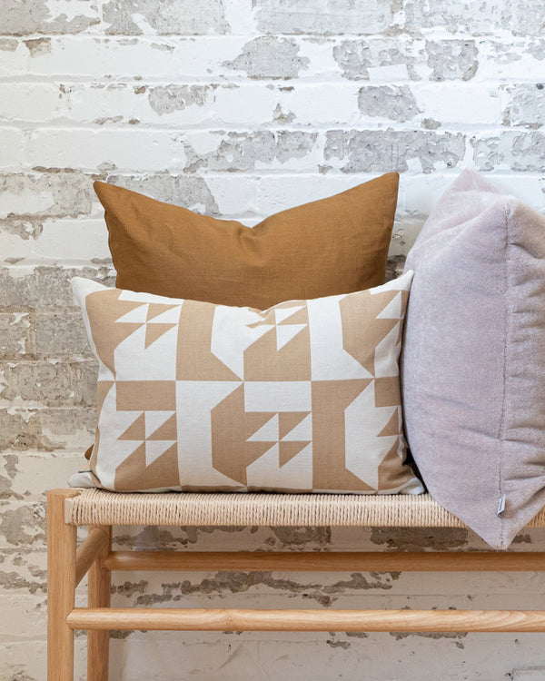 Solid linen ginger pillow on bench with complimentary geometric beige pillow