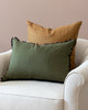 Solid linen ginger pillow on white arm chair with complementary green pom pom pillow