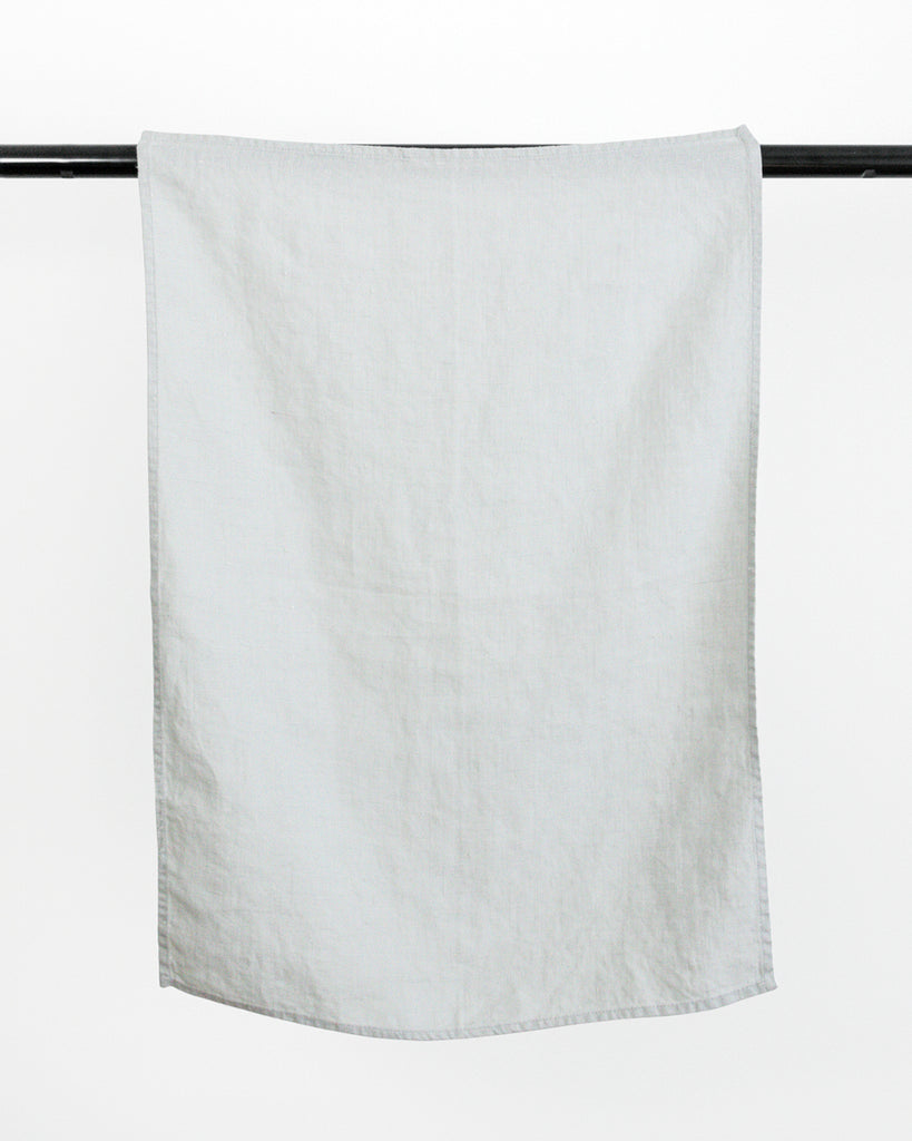 Blue stonewashed linen tea towel hanging on black rod