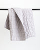 Classic light grey quilt folded over black rod