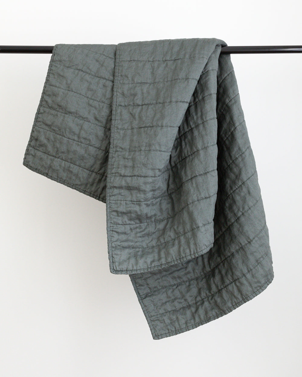 Dark green colour handmade Linen Quilt folded over black rod