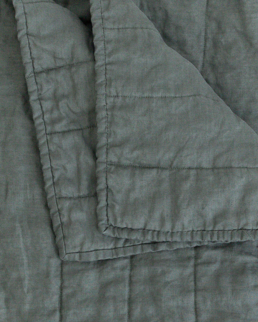 Close up detail of folded dark green colour handmade Linen Quilt
