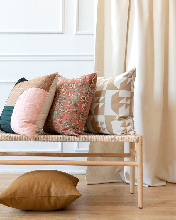 Beige vintage fabric, inspired by quilted patchwork pillow on bench with complimentary Hemme pillows beside it.