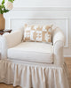 Beige vintage fabric pillow on white arm chair.