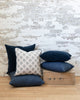 Midnight blue velvet pillow sitting on pillow stack with complimentary blue pillows