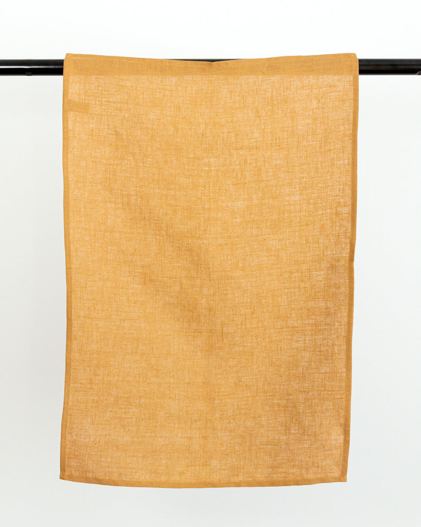  linen tea towel in brown earth-tone hanging on black rod